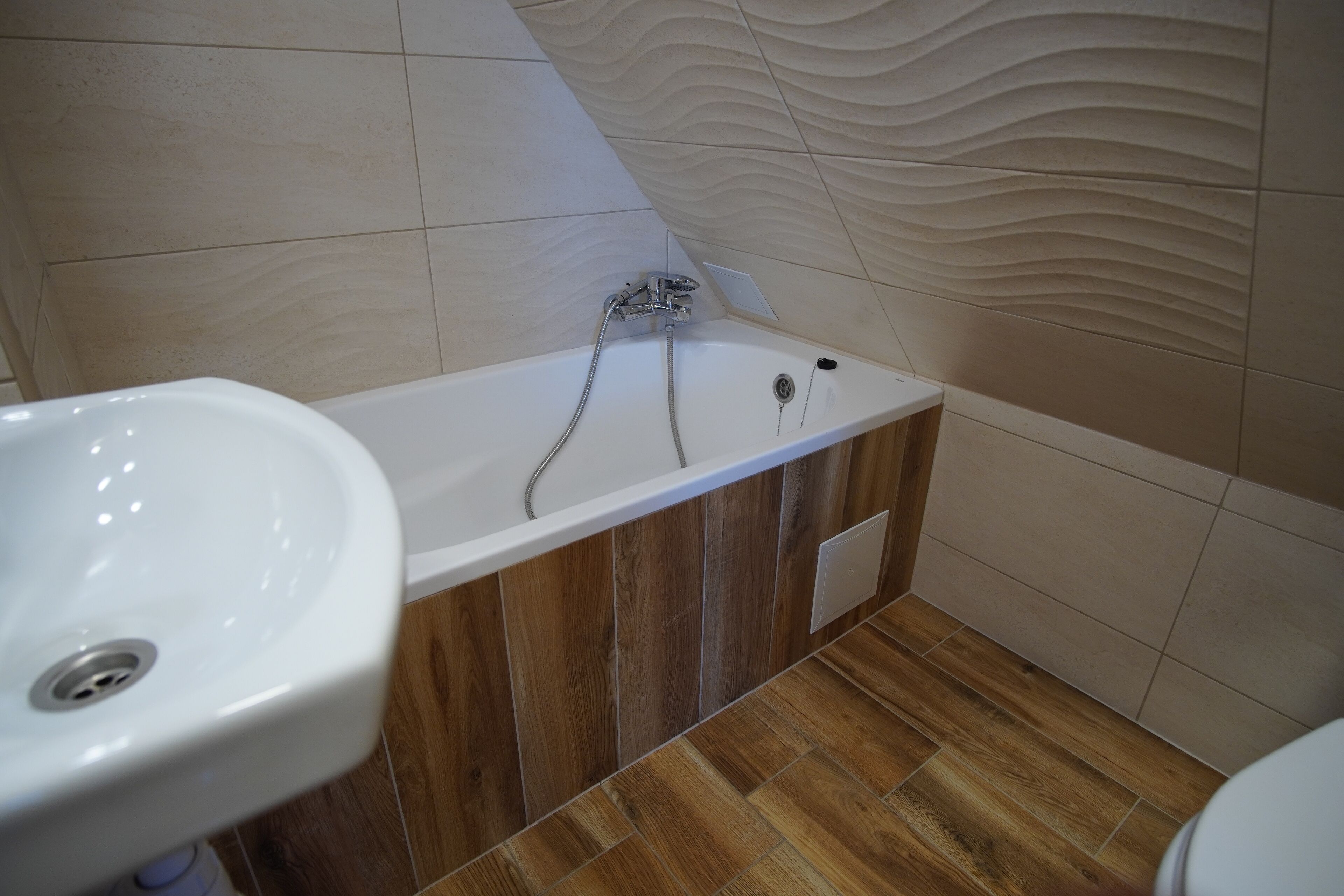 Un baño con bañera, lavabo y suelo de madera.