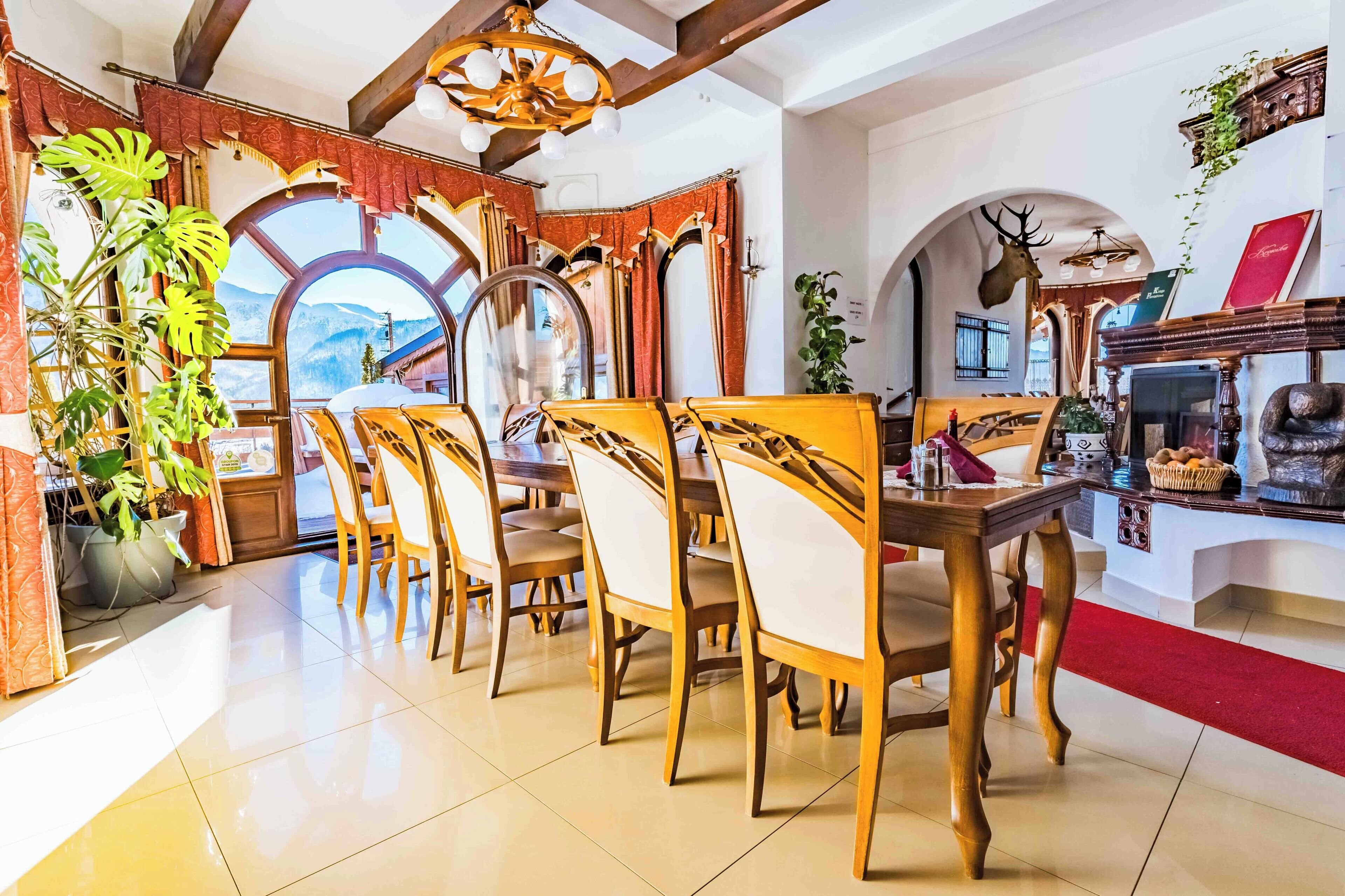 A dining area with wooden chairs and tables, a fireplace, and a large window with a mountain view.