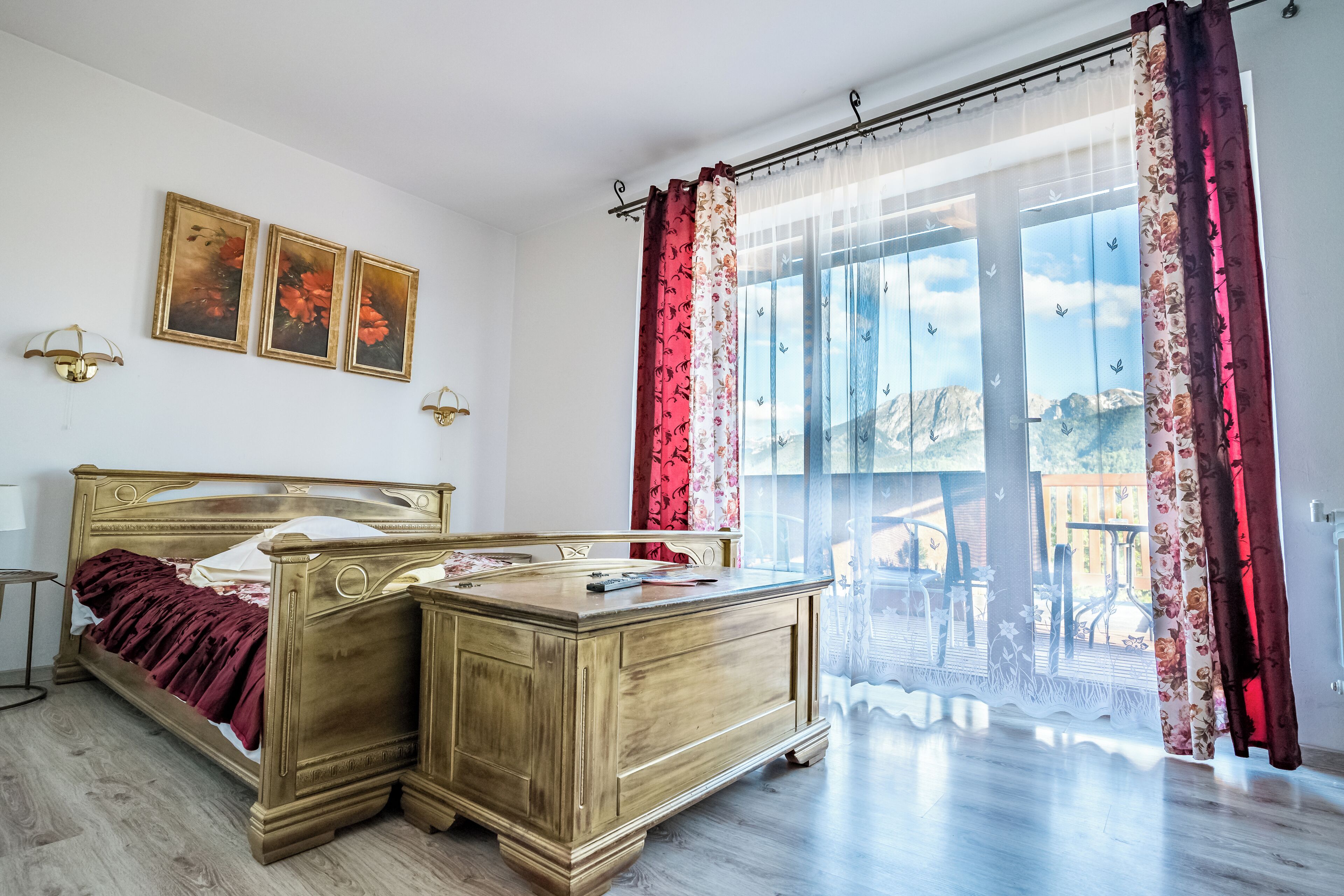Un dormitorio con una cama de madera, una mesita de noche y un ventanal con cortinas.