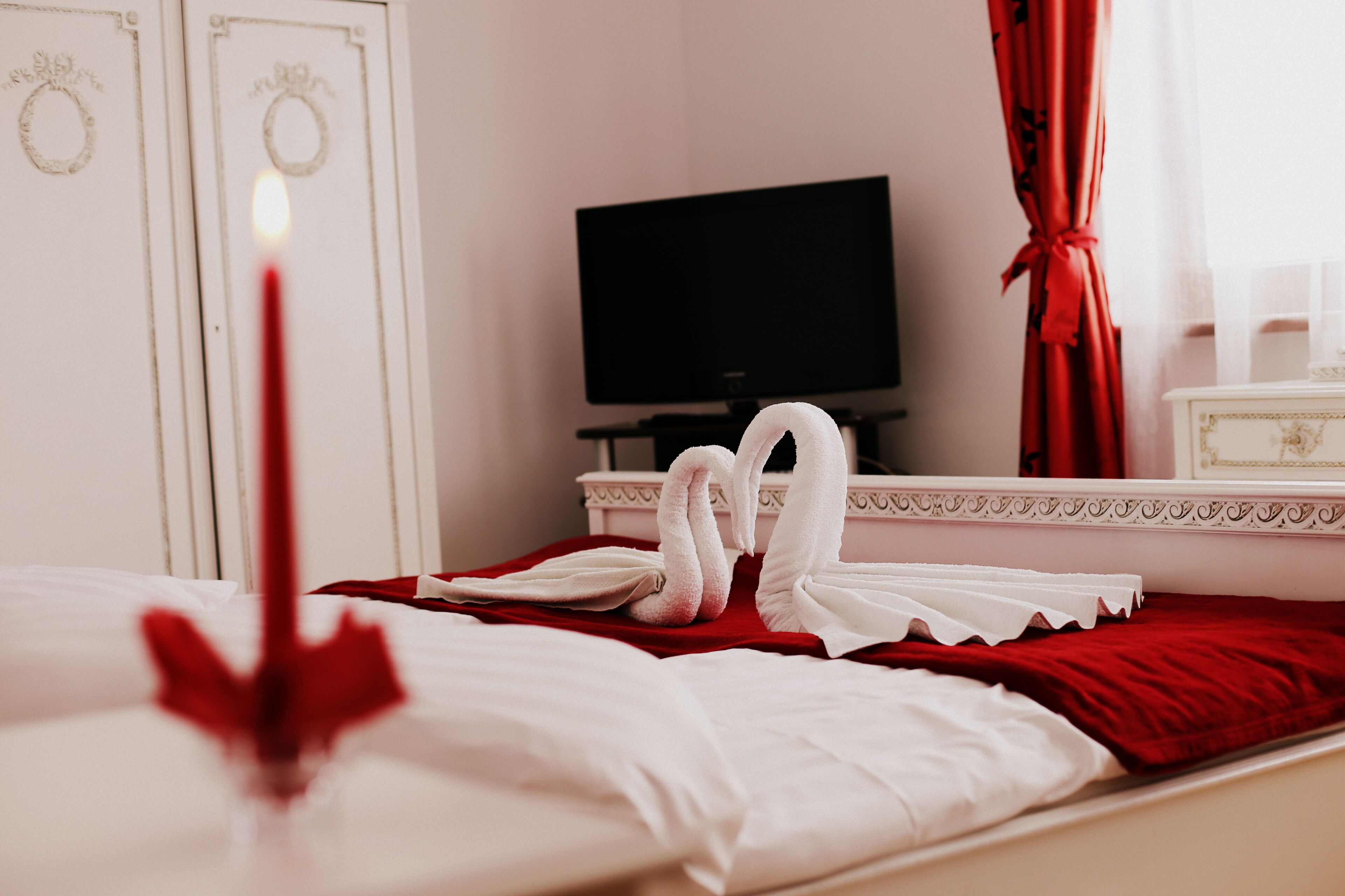 Ein Hotelzimmer mit Bett, Fernseher und einem roten Vorhang.