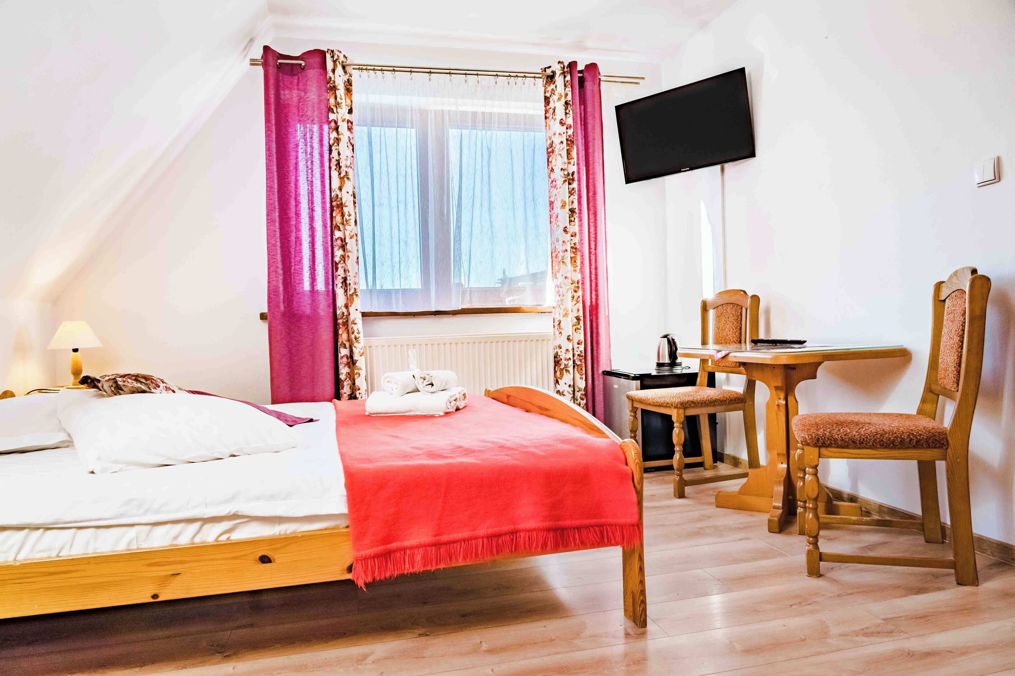Un dormitorio con cama, escritorio, silla y televisor.