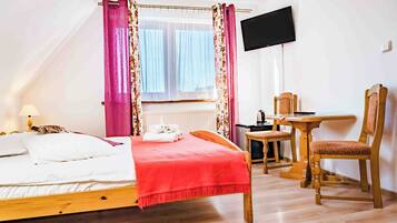 Een slaapkamer met een bed, een bureau, een stoel en een televisie.