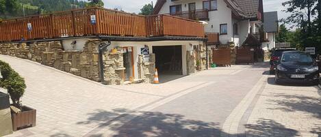 A stone building with a wooden deck, a garage, and a car parked in front.