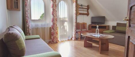 Una sala de estar acogedora con un sofá, una mesa de centro de madera y un televisor sobre un mueble.