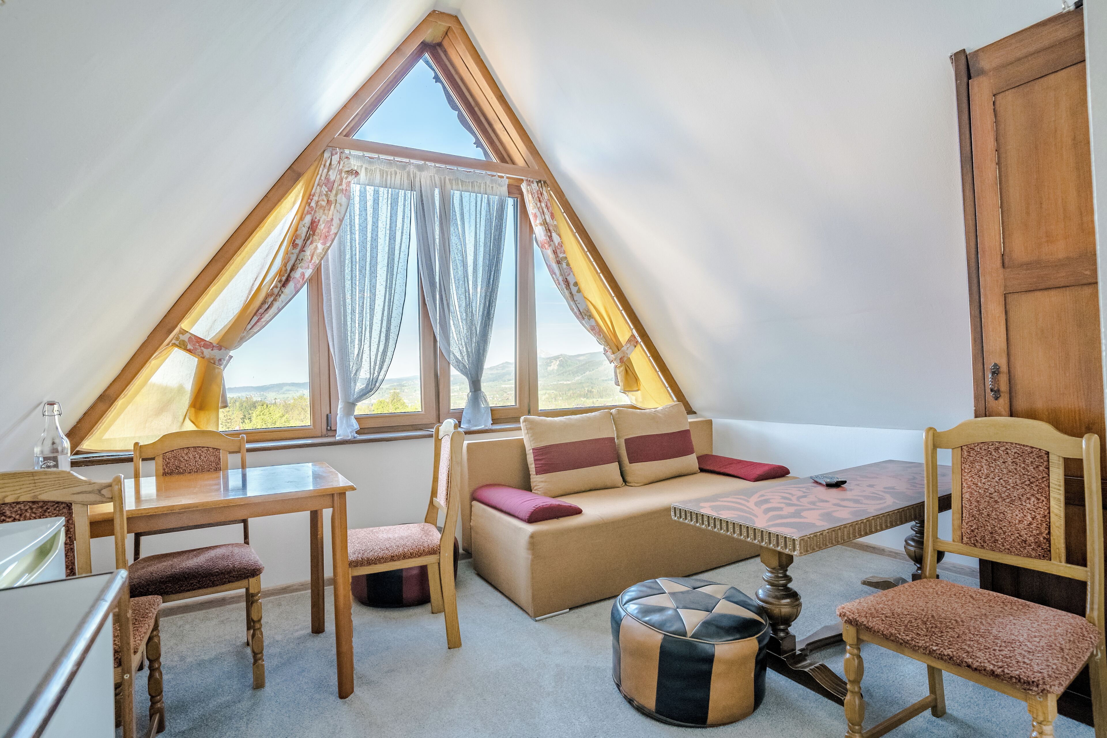 Une pièce chaleureuse avec un plafond en pente, un canapé, une table à manger et des chaises.