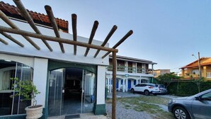 Un edificio con un acceso cubierto, una planta en maceta y un coche estacionado en la entrada.