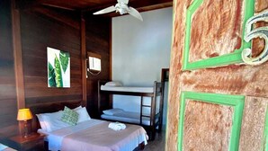 Una habitación con dos camas, un ventilador de techo y una puerta con el número 5.