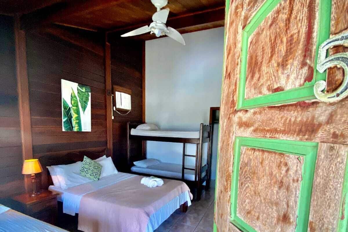 Une chambre avec deux lits, un ventilateur de plafond et une porte portant le numéro 5.