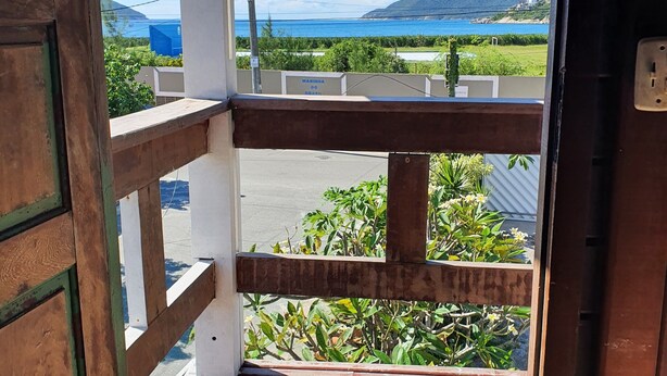 Un balcón de madera con vistas al mar y a la montaña.