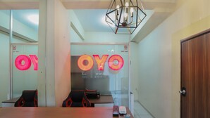 A hotel reception area with a wooden reception desk, a glass partition with 'OYO' signage, and a 'STAFF ONLY' sign. - OYO 2103 Lauv Room 2 Grand Centerpoint Tower B (Bekasi)