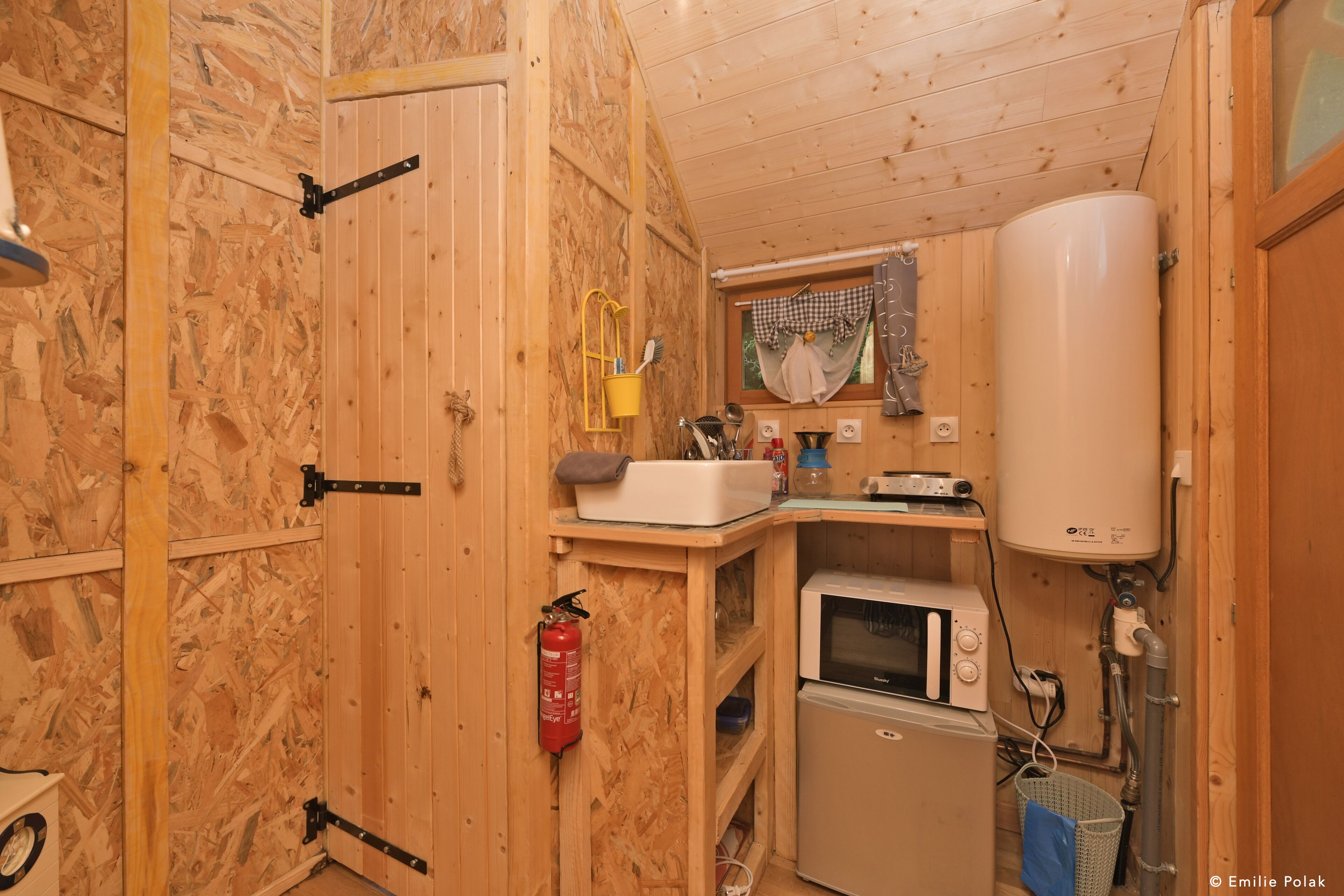 A compact kitchen with a microwave, sink, and water heater.