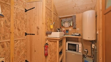 A compact kitchen with a microwave, sink, and water heater.
