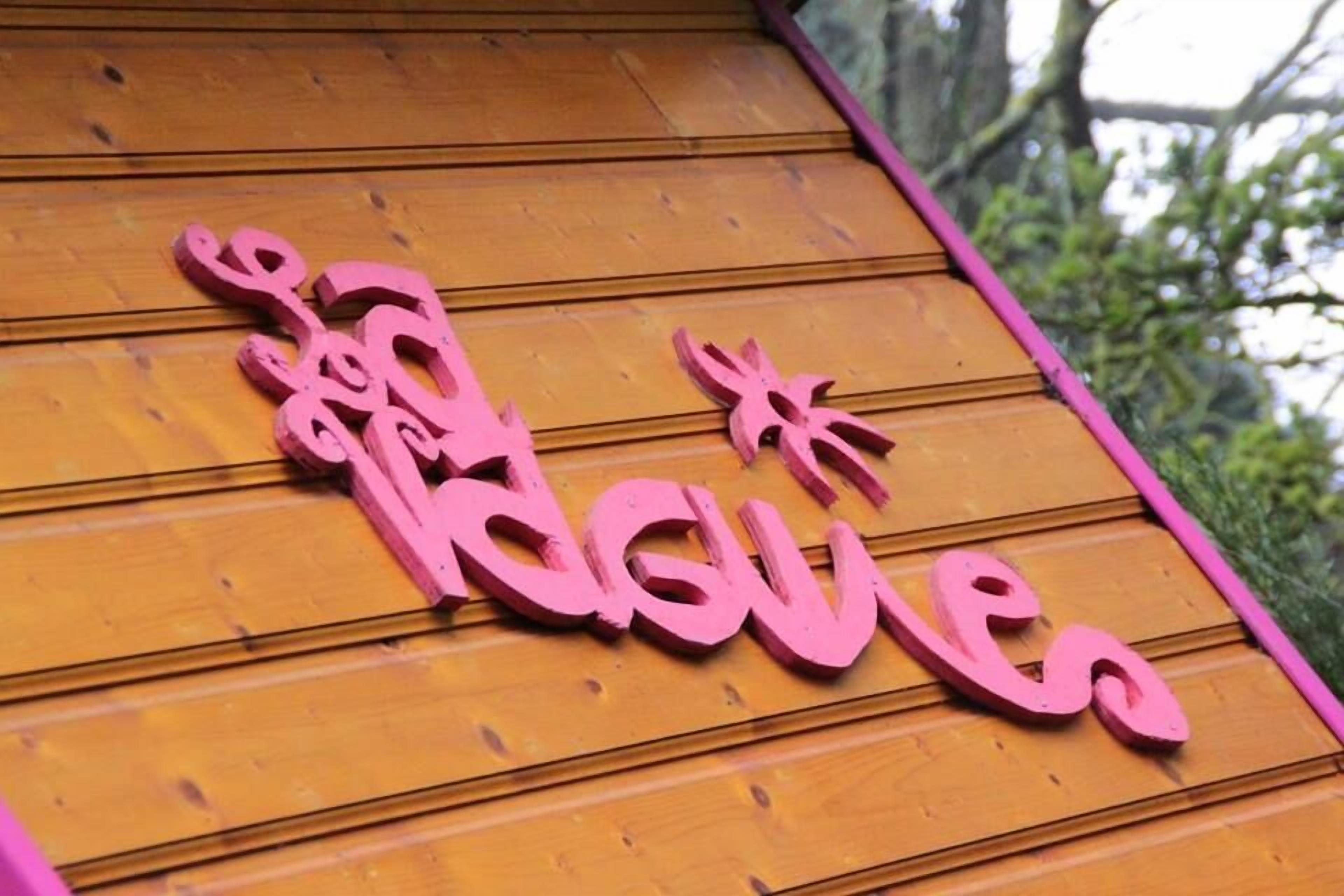 A wooden sign with pink lettering spelling "Kusai" on a wooden surface.