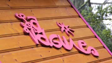 A wooden sign with pink lettering spelling "Kusai" on a wooden surface.