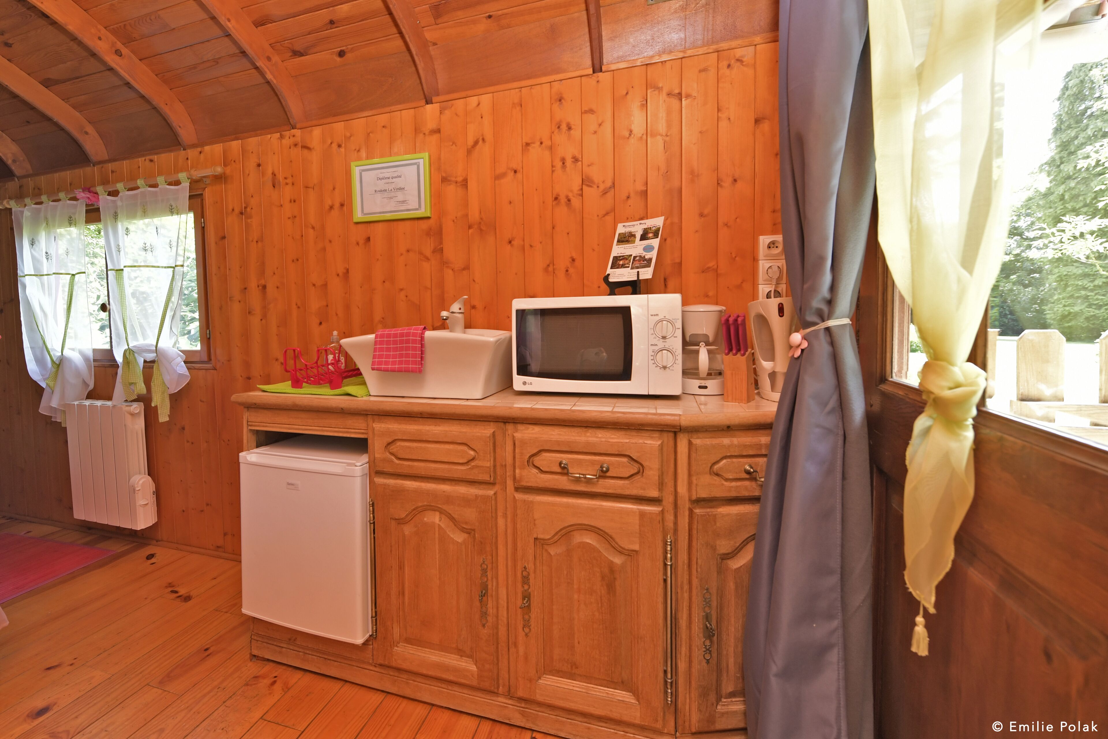 L’intérieur d ’une cabane en bois comprend un coin cuisine équipé d’un four à micro-ondes, d’un petit réfrigérateur et d’une armoire en bois.