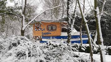 Una cabaña de madera con un letrero que dice "Domi" en un paisaje nevado de bosque.