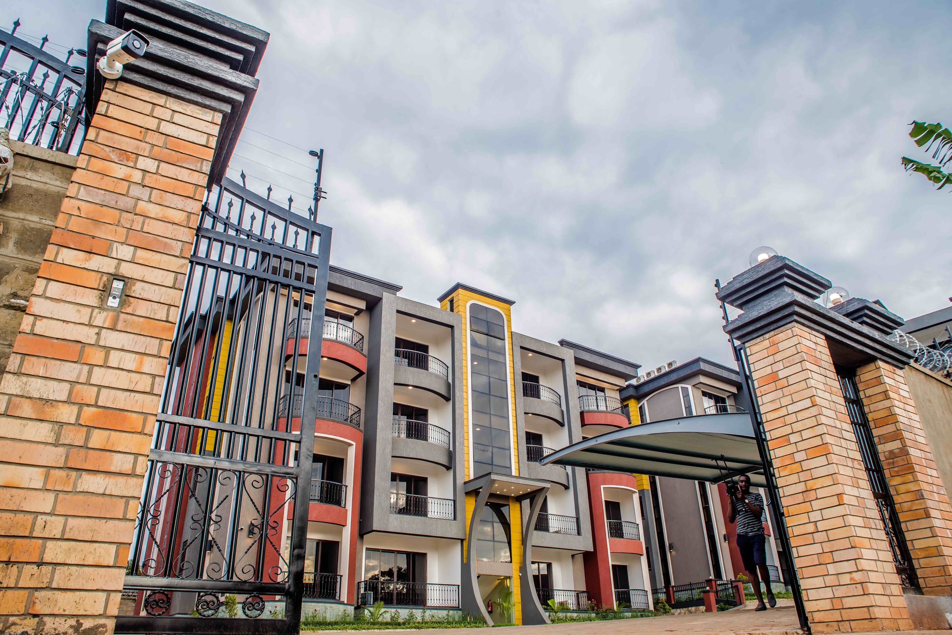A multi-story building with a gated entrance, balconies, and a covered walkway.