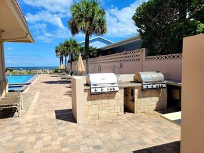 An outdoor patio with a barbecue grill, a pool, and lounge chairs. - 106 - 2/2 Newly Renovated Fabulous Condo (New Smyrna Beach)