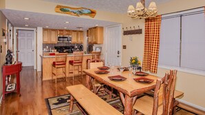 A spacious kitchen with wooden cabinets, a dining area with a wooden table and chairs, and a chandelier. - Happy Trails- easy access, 3 minute drive to Pigeon Forge (Pigeon Forge)
