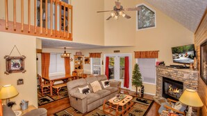 A cozy living room with a fireplace, a dining area, and a loft space. - Happy Trails- easy access, 3 minute drive to Pigeon Forge (Pigeon Forge)