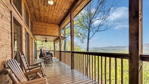 A wooden porch with Adirondack chairs, a ceiling fan, and a view of a forested landscape. - Smoky Mountain Views  - AWESOME MOUNTAIN VIEWS, $560 FREE tickets each paid day (Sevierville)