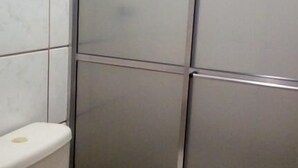 A bathroom with a toilet, a shower enclosure, and tiled walls. - Hotel Pousada Mosaico (Palmas)