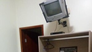 A room with a bed, a television mounted on a wooden cabinet, and a door leading to another room. - Hotel Pousada Mosaico (Palmas)