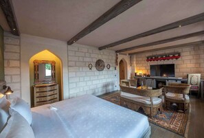 Une chambre avec un grand lit, une commode, une télévision et une cheminée.