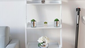 Une étagère blanche agrémentée d’objets décoratifs, d’une petite plante et d’un porte-bougie.
