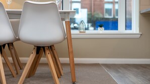 Un coin repas avec une table et des chaises, une fenêtre donnant sur des bâtiments et un petit objet décoratif posé sur le rebord de la fenêtre.