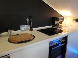A modern kitchen with a built-in stove, oven, and a cutting board on the countertop.