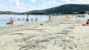 A beach with people swimming and walking, tents, and boats on the water. - Breakfast on the balcony with Treehouse vibe, garden, barbecue, reservoir, thermal spa (Nordhalben)