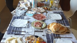 A dining table set with various food items and utensils, including bread, cheese, and fruits. - B&B Lavika Pedara (Pedara)