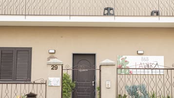 Un edificio a due piani con un balcone, una porta con una targa e un cancello.