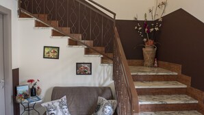 A staircase with marble steps, a sofa with cushions, a coffee table with magazines, and a wall-mounted sign reading "B&B LAVIK." - B&B Lavika Pedara (Pedara)
