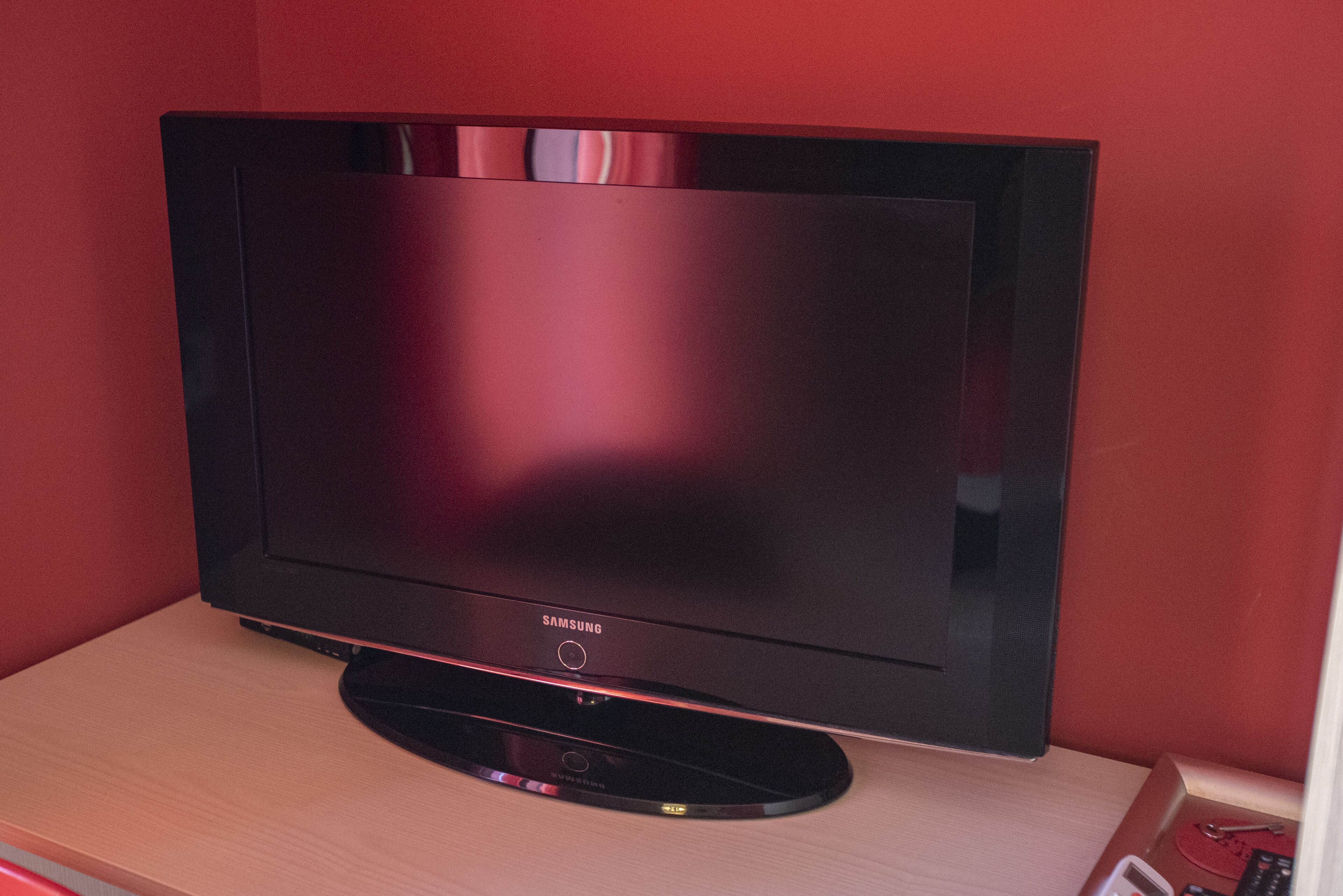 A Samsung flat-screen TV on a wooden stand in a room with red walls.