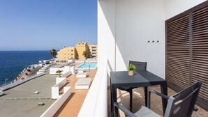 A balcony with a pool, a table, and chairs, overlooking a coastal area with buildings and the sea. - Encantador apto. Vistas al mar.WIFI (Callao Salvaje)