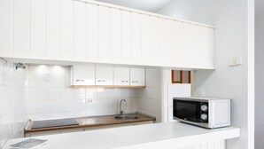 A compact kitchen with white cabinetry, a built-in microwave, and a wooden countertop. - Encantador apto. Vistas al mar.WIFI (Callao Salvaje)