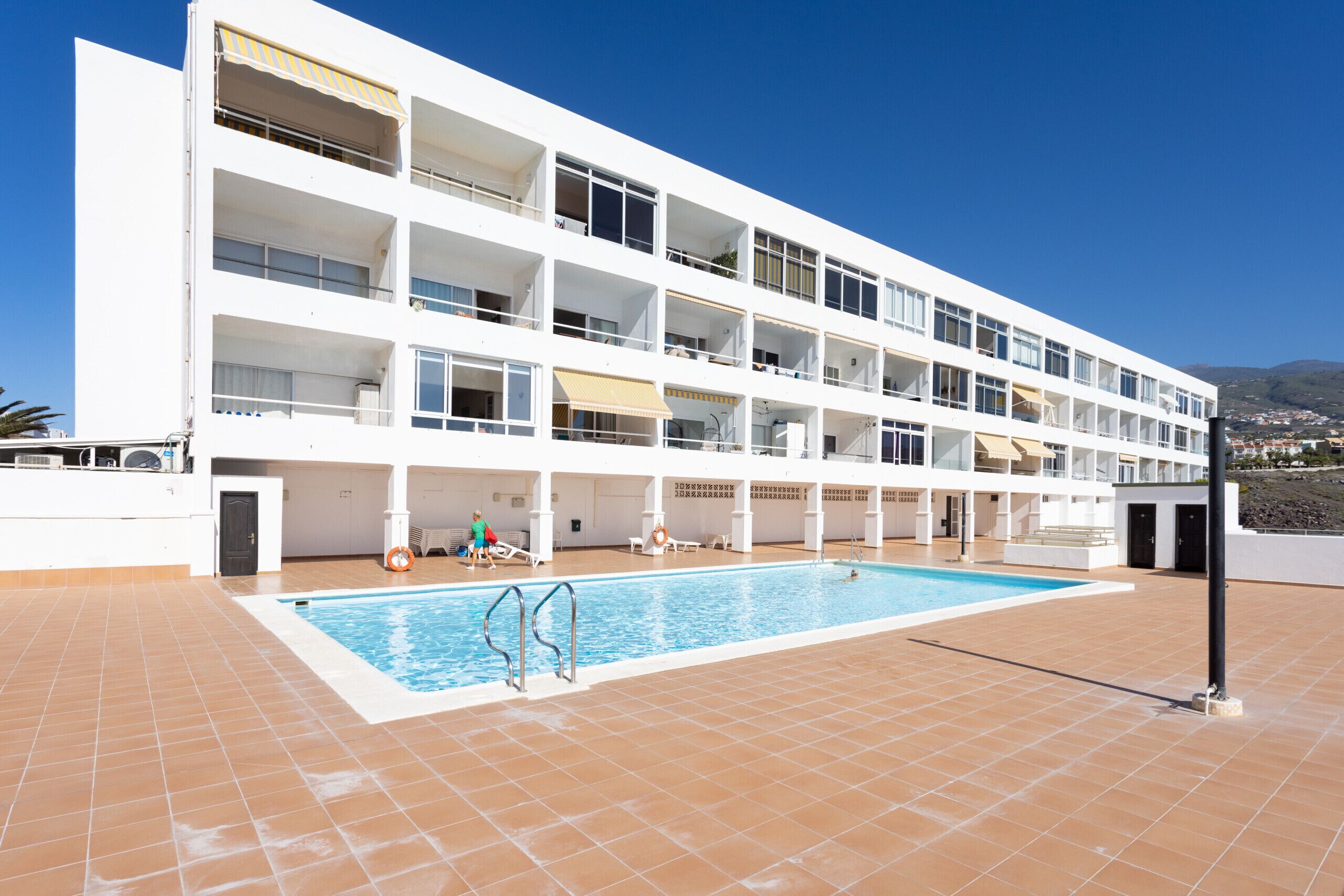 A multi-story hotel with a swimming pool on the ground floor.