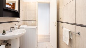 A modern bathroom with a white sink, a mirror, a towel rack, and a door leading to another room. - Encantador apto. Vistas al mar.WIFI (Callao Salvaje)