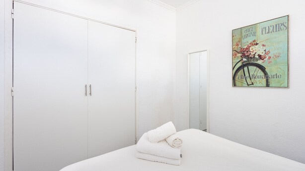 A bedroom with a white bed, a white wardrobe, and a wall-mounted picture of a bicycle. - Encantador apto. Vistas al mar.WIFI (Callao Salvaje)