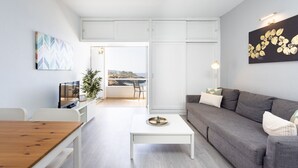 A modern living room with a sofa, a coffee table, a TV, and a view of the sea. - Encantador apto. Vistas al mar.WIFI (Callao Salvaje)