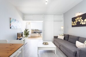 Una sala de estar moderna con un sofá, una mesa de centro, un televisor y vistas al mar.