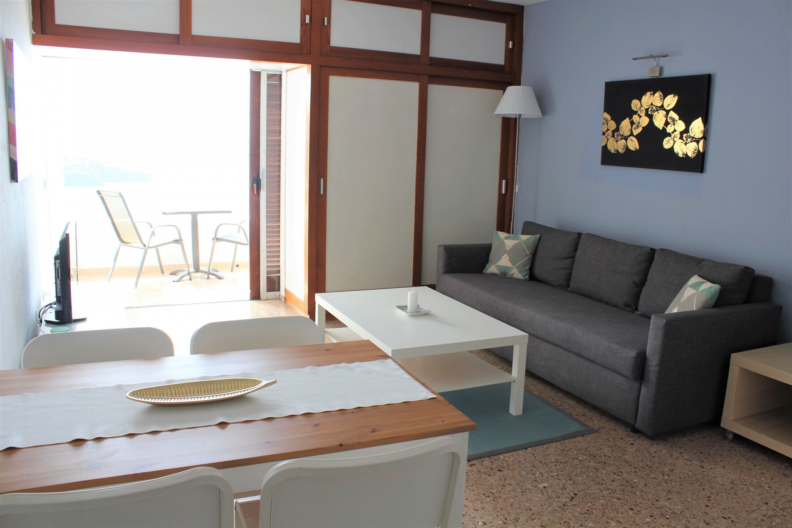A living room with a sofa, a coffee table, and a dining table with chairs.