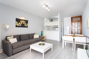 Un salon moderne avec un canapé gris, une table basse blanche et un tableau accroché au mur.