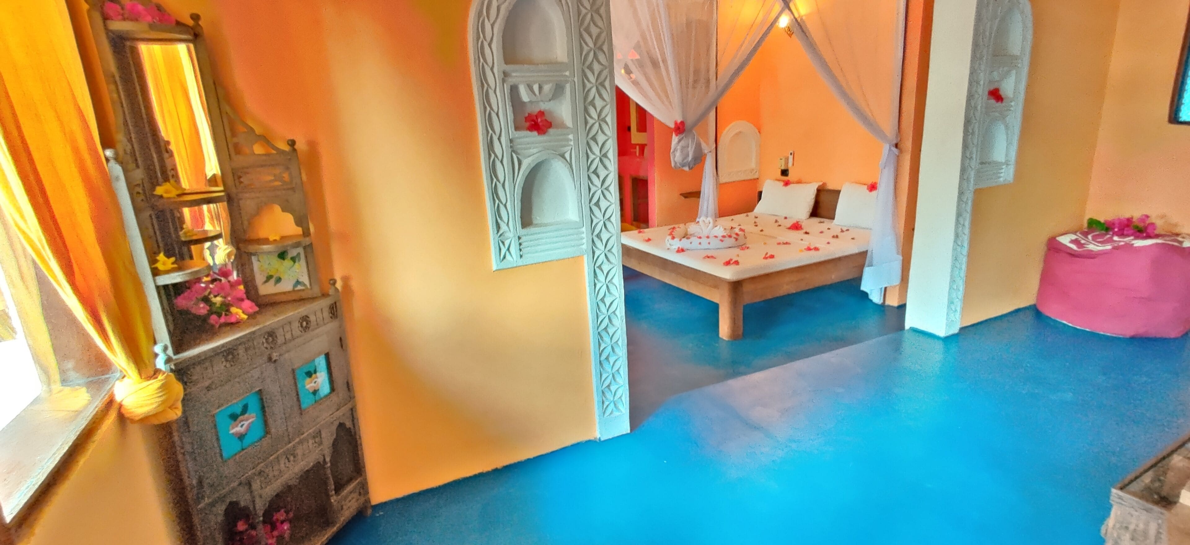 Un dormitorio con una cama bajo un dosel, una mesita de noche y un adornado en la pared.