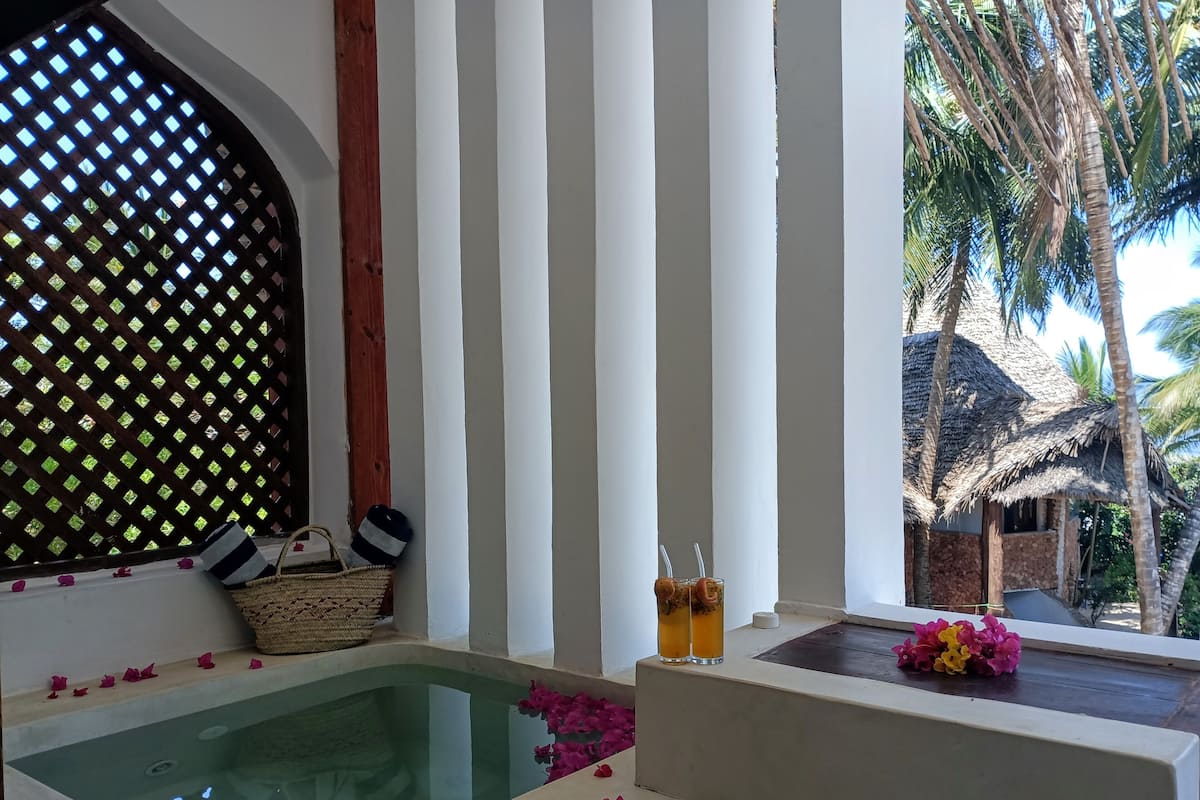 A spa area with a hot tub, a wooden lattice wall, and a view of palm trees.