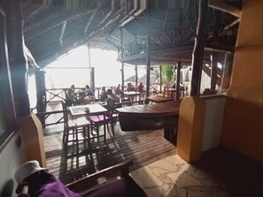 An outdoor dining area with tables and chairs, a covered seating area, and a view of the surrounding landscape. - Villa Dida Resort (Pwani Mchangani)