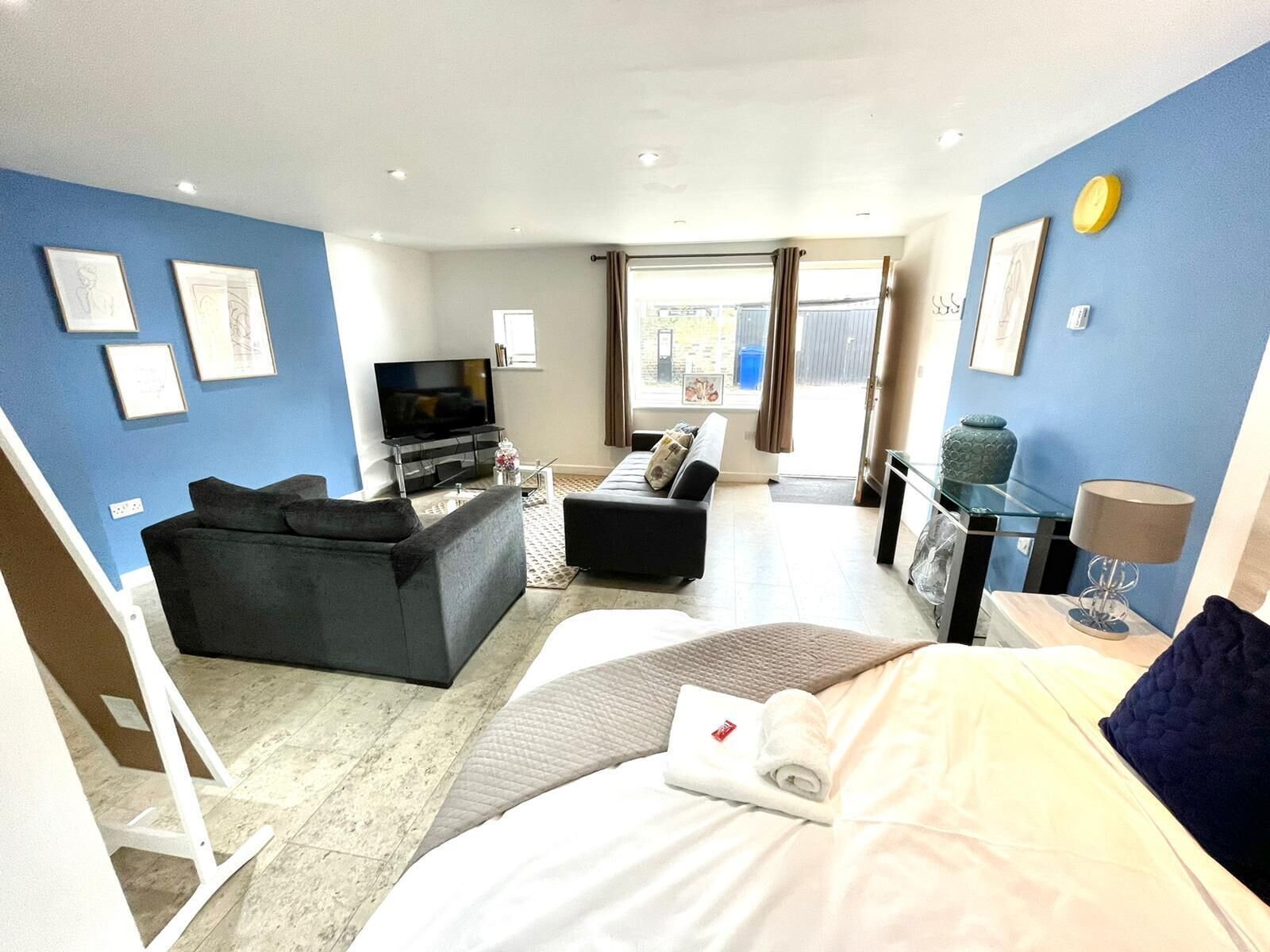 A modern hotel room with a bed, a sofa, a TV, and a dining area.