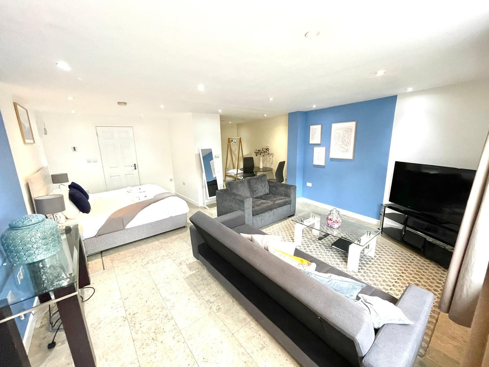 Una sala moderna con un sofá, televisor y cama.